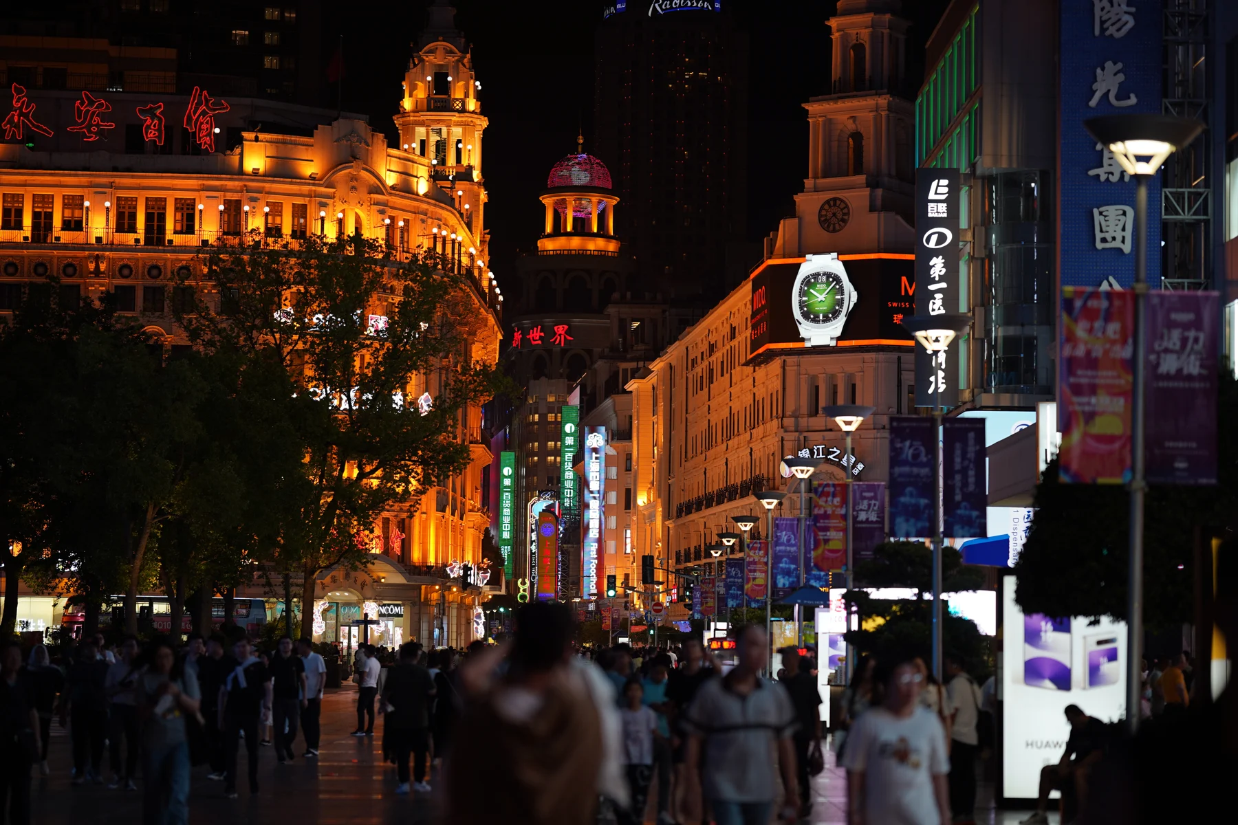 Shoppers and illuminated shop signs on Nanjing Road at night in Shanghai