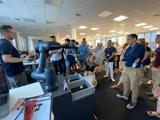 Esade and CaixaBank EmprendeXXI participants gathered around a robot-arm demonstration during their Munich immersion in July 2023.