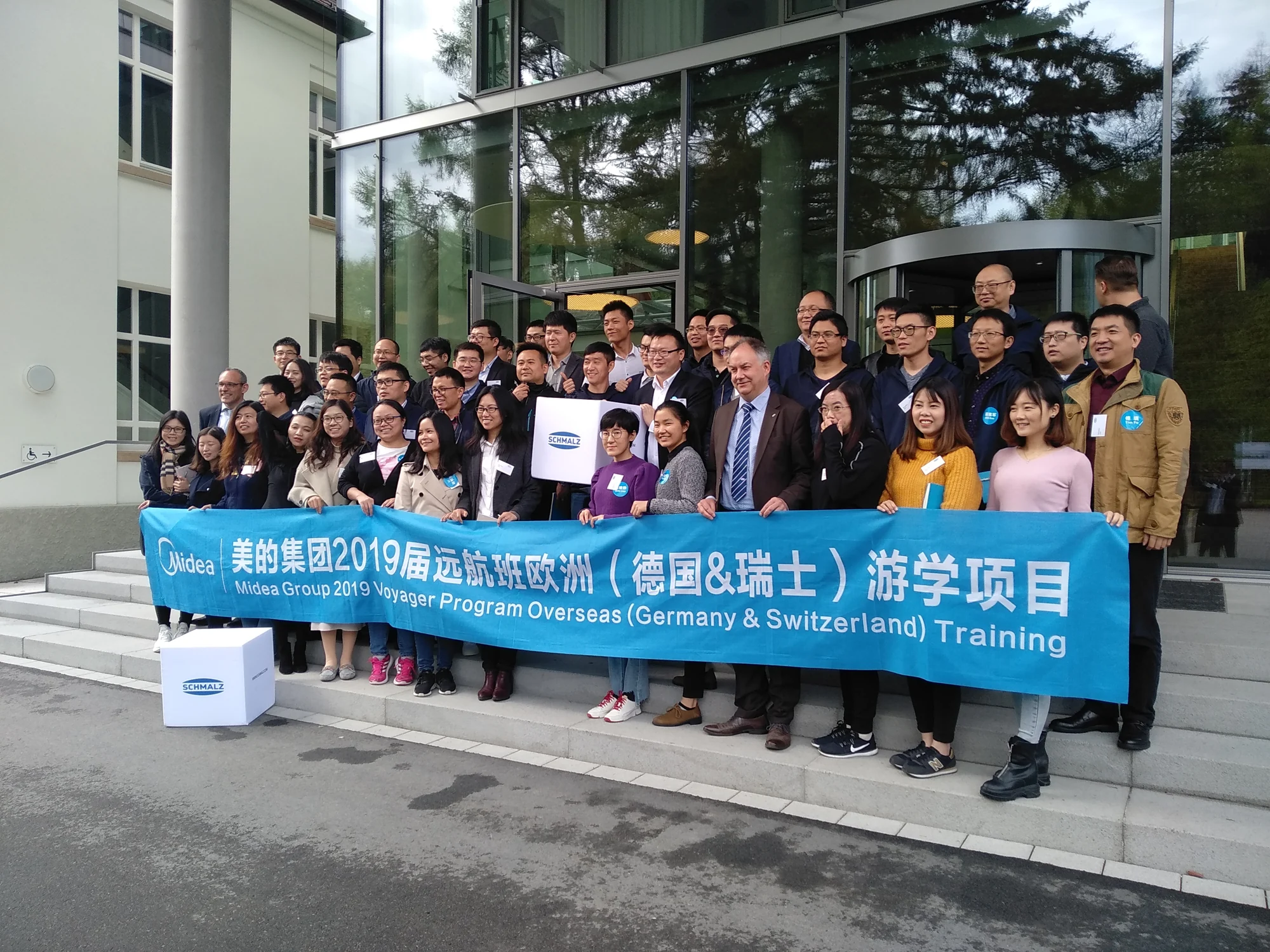 Midea Voyager participants outside Schmalz with a banner identifying their 2019 Germany and Switzerland training program.