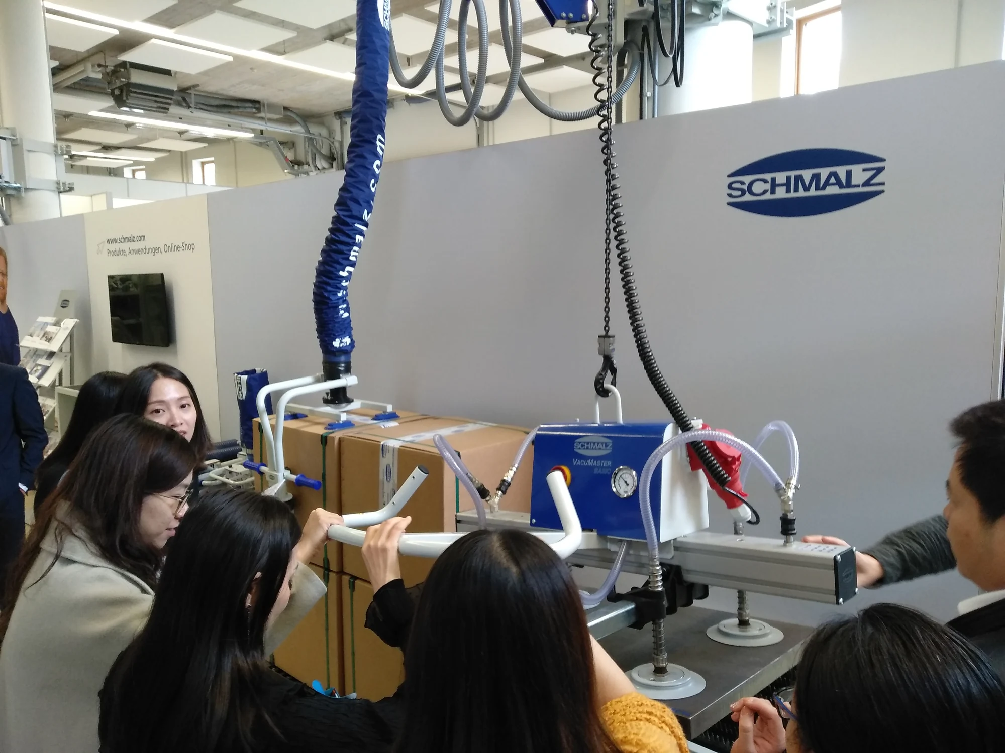 Delegates trying vacuum lifting equipment during a company visit to Schmalz.