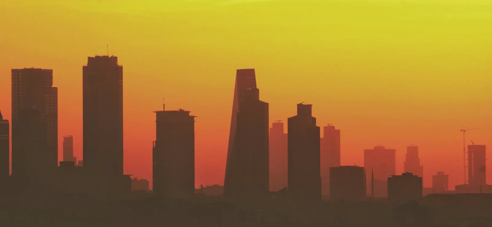 A close view of the modern towers of Levent, Istanbul, silhouetted against an orange sunset