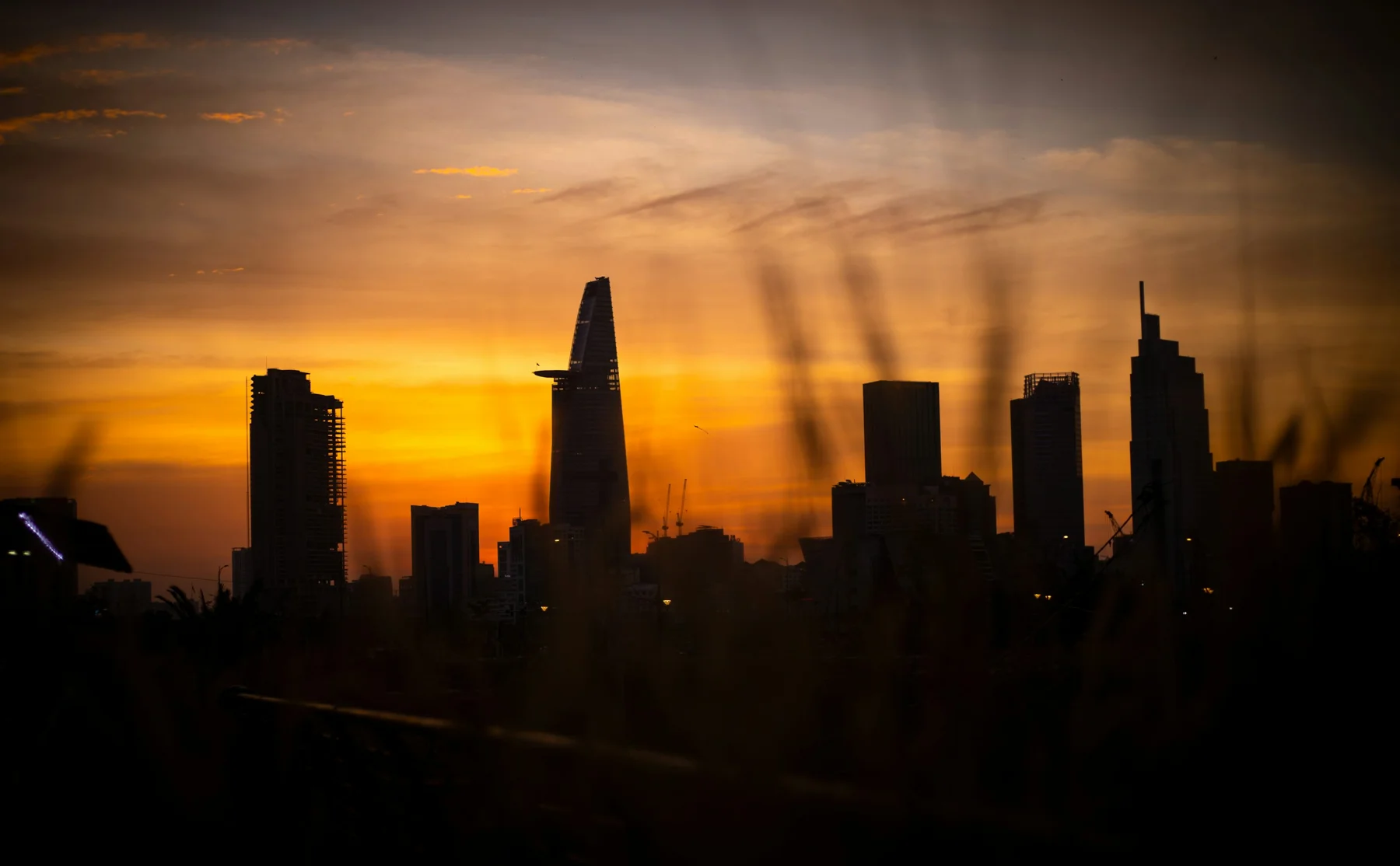 Ho Chi Minh City’s skyline at sunset, with the Bitexco tower silhouetted against the sky